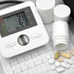 Blood pressure monitor with pills on ECG sheet, essential for heart health management.